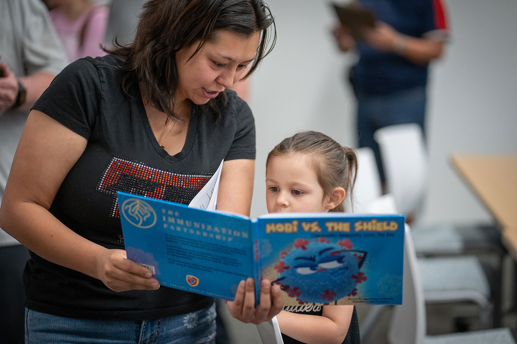 Woman and young daughter read a book